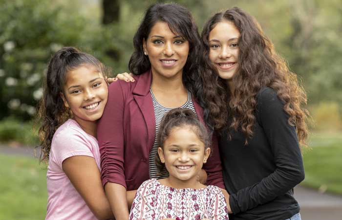 A mother and her three daughters smiling outside