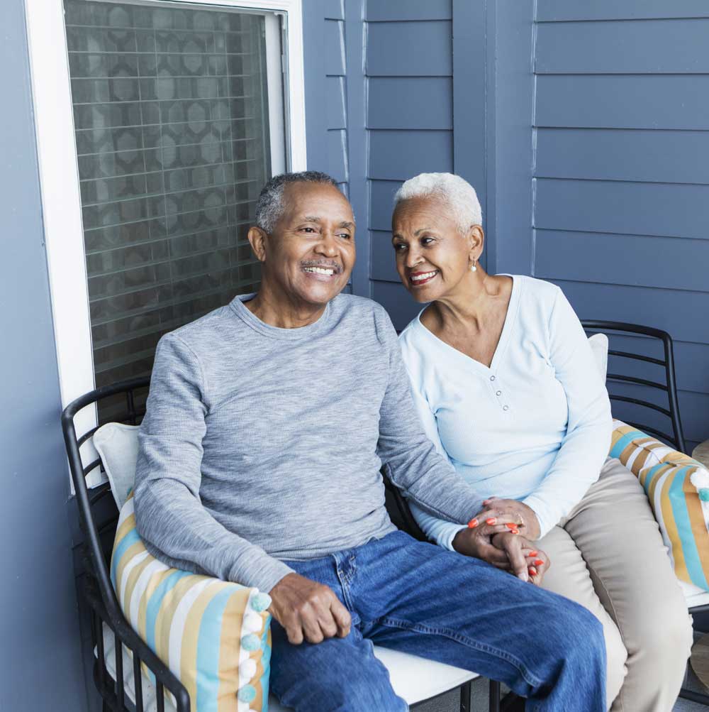 Older couple smiling while sitting on a porch